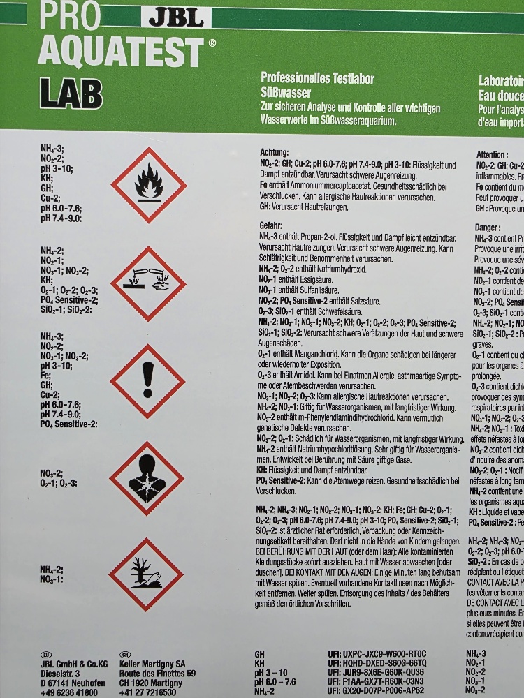 Etikett des JBL ProAquaTest LAB Wasseranalyse-Kits mit Logo und Produkttitel. Zeigt fünf rote Gefahrensymbole (Entflammbar, ätzend, reizend, Gesundheits- und Umweltgefahr). Darunter Parameter wie pH, KH, NH3, NO2 sowie Sicherheits- und Warnhinweise.